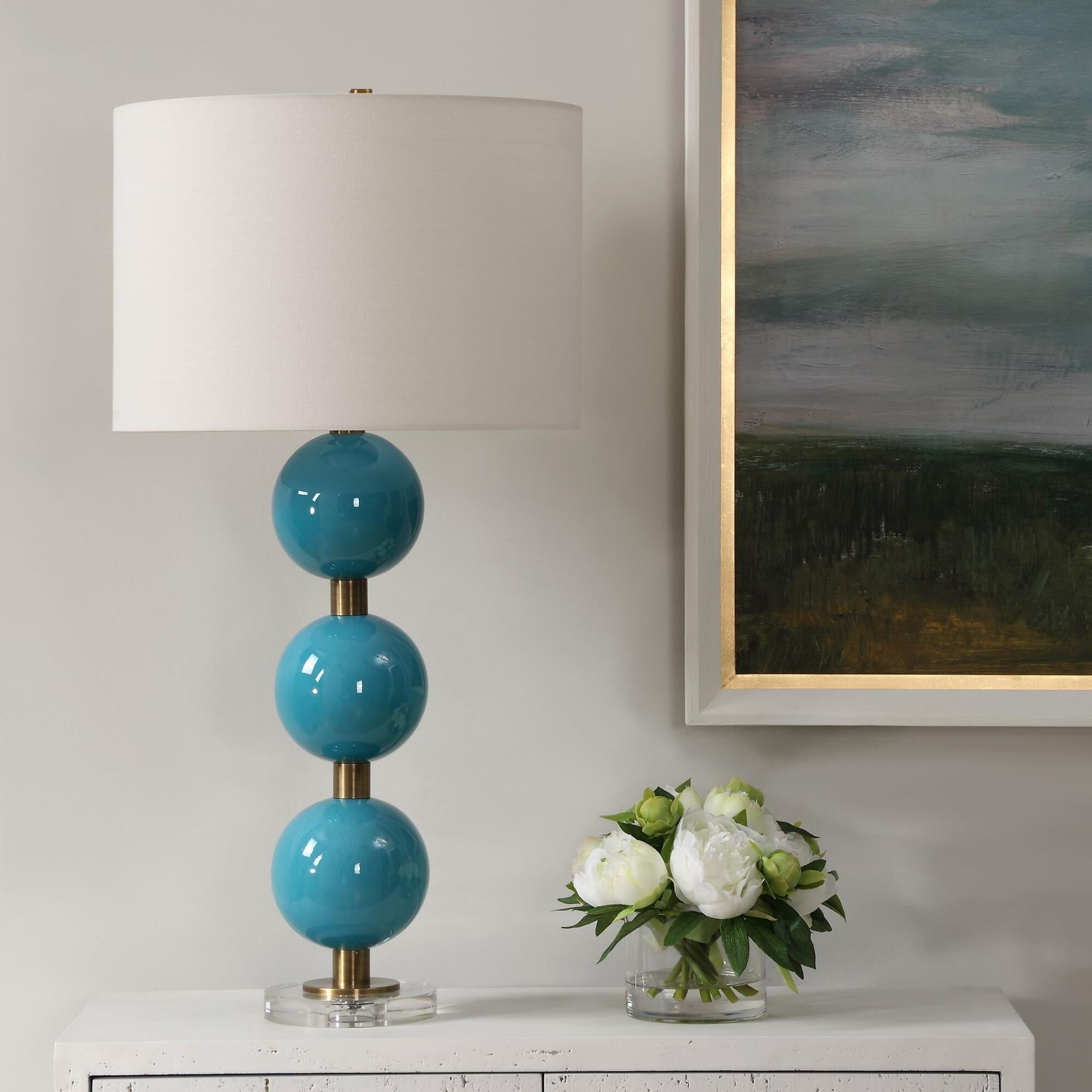 Shown in Elevate Your Space With Our Captivating Table Lamp Featuring Stacked Ceramic Spheres Adorned In A Cr finish and Round Drum Hardback shade