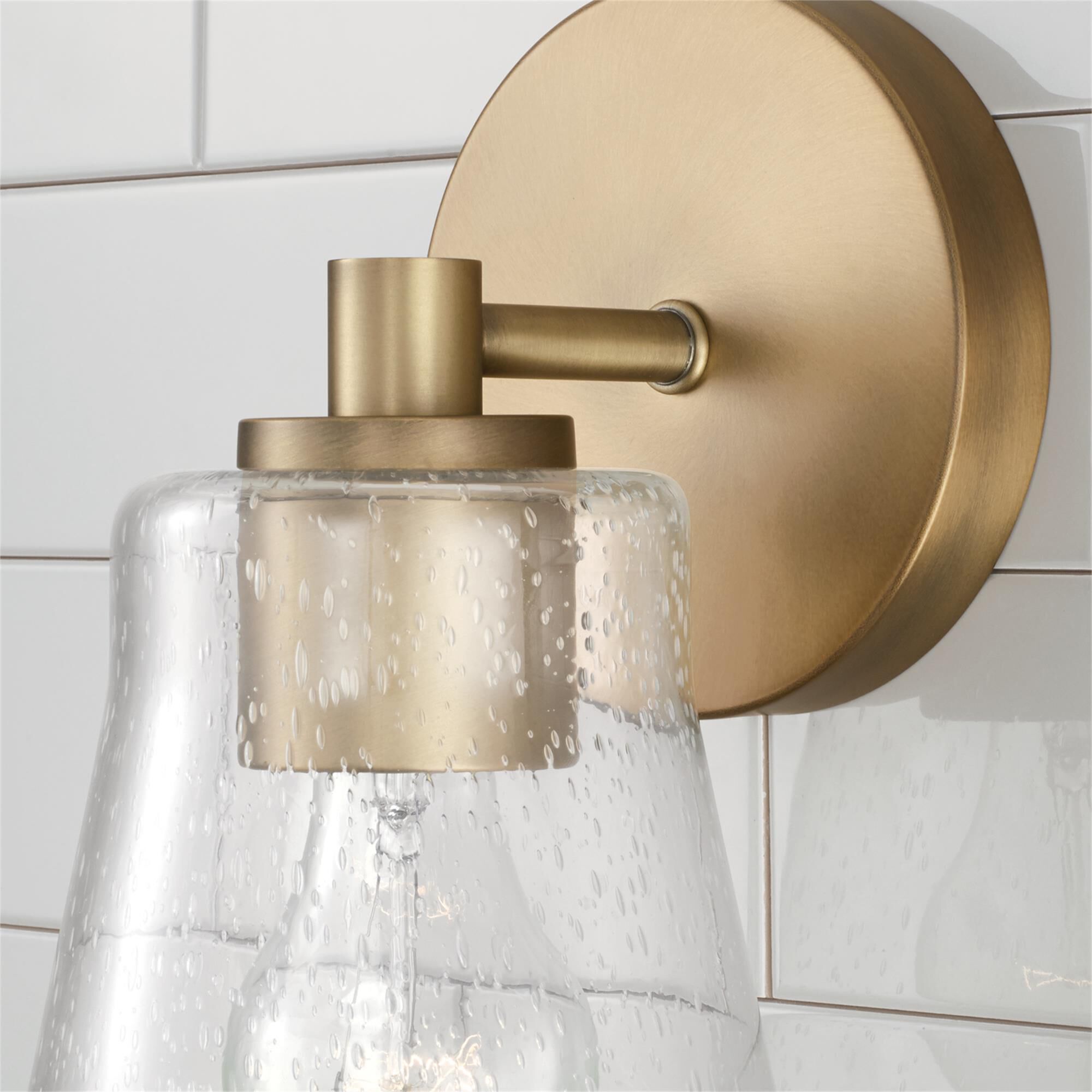 Shown in Aged Brass finish and Clear Seeded glass