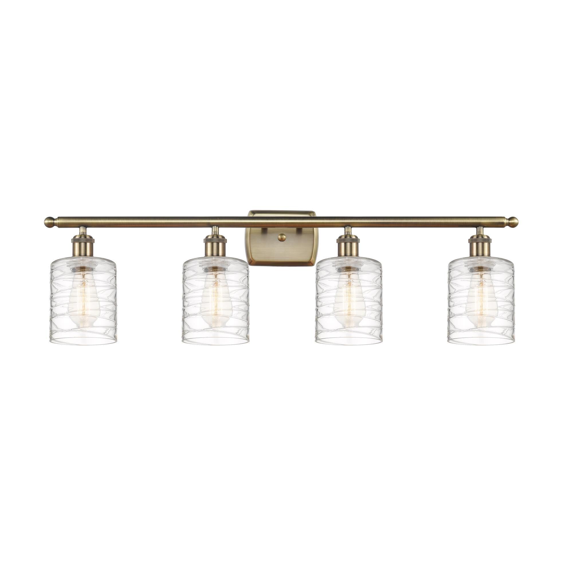 Shown in Antique Brass finish and Deco Swirl Cobbleskill glass