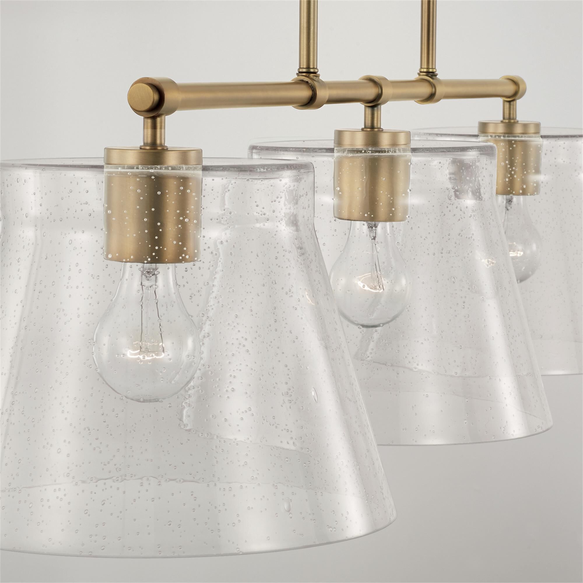 Shown in Aged Brass finish and Clear Seeded glass