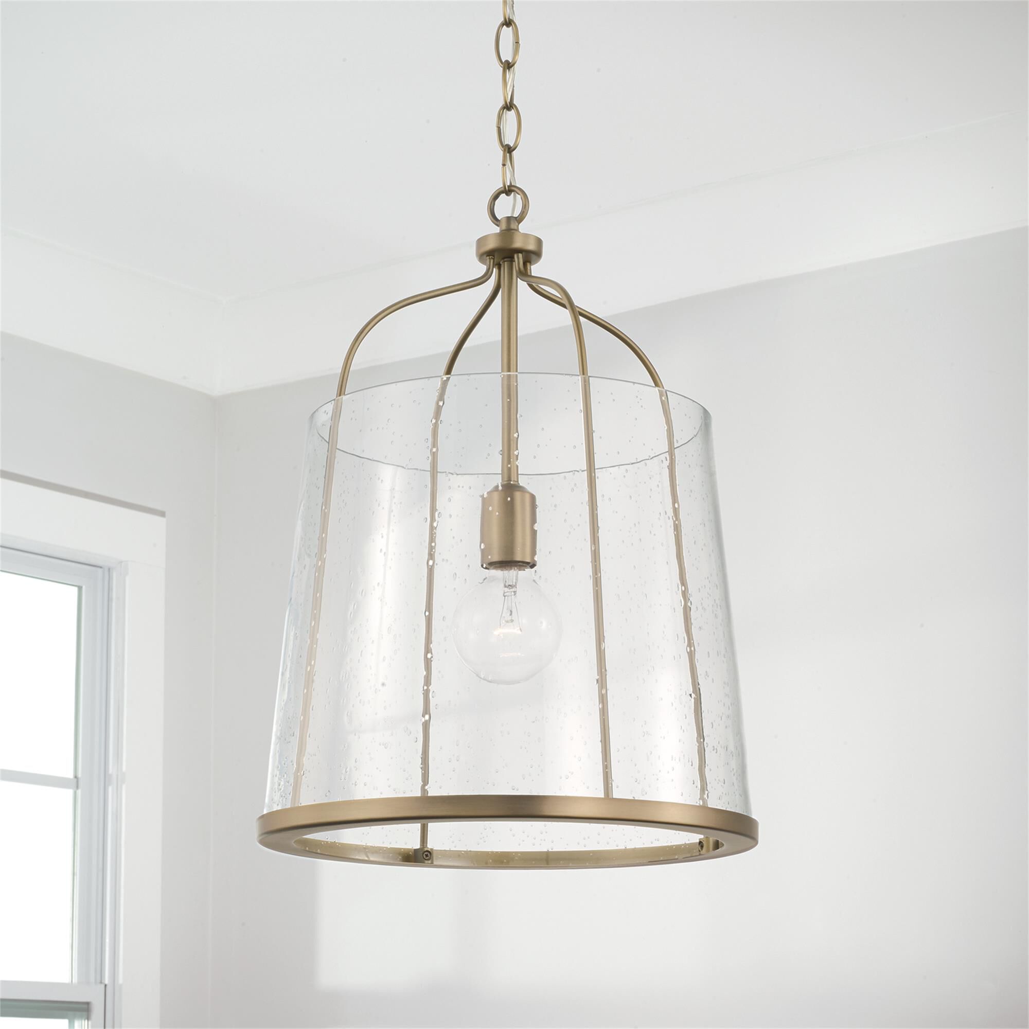 Shown in Aged Brass finish and Clear Seeded glass