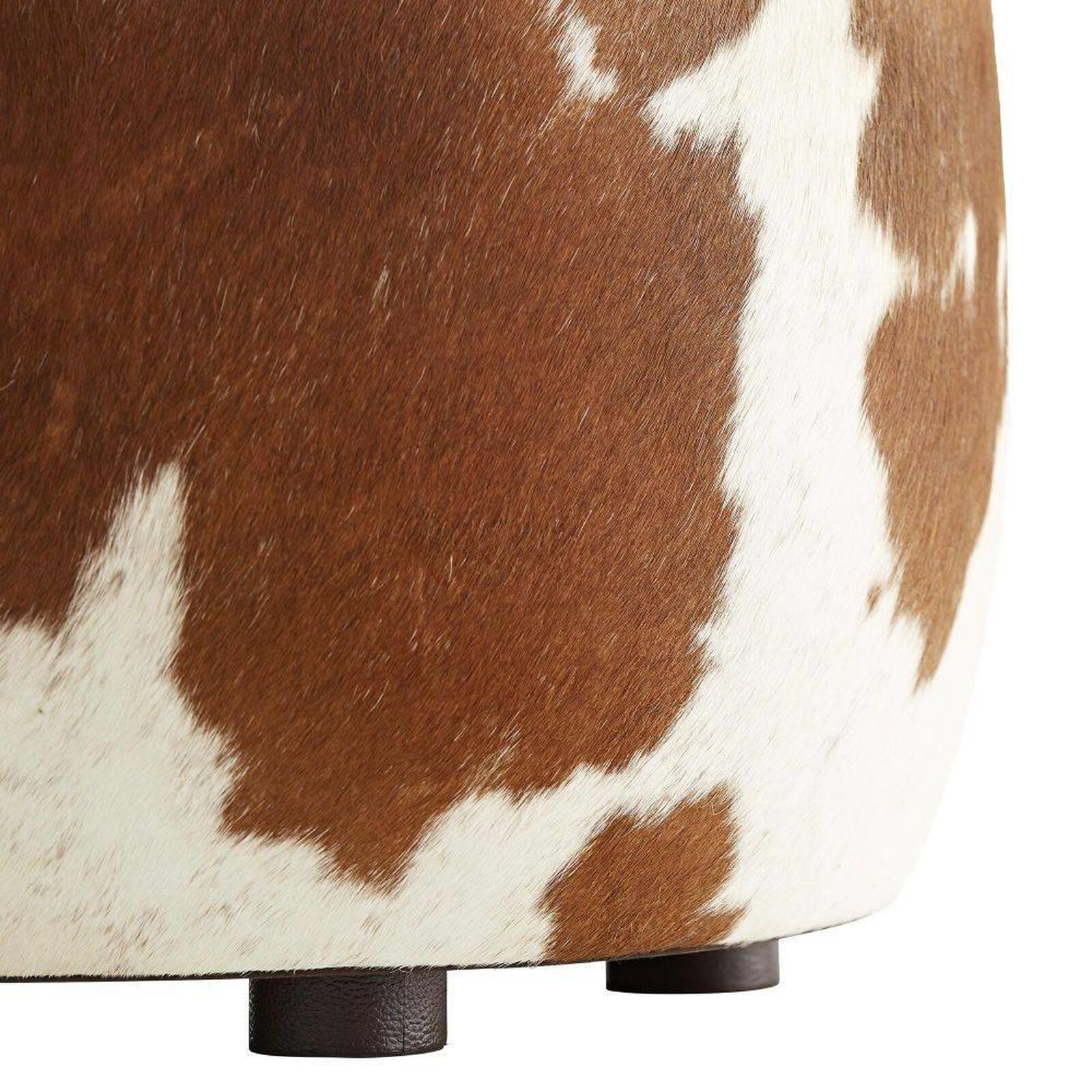 Full view of the brown and white cowhide ottoman with dark feet.