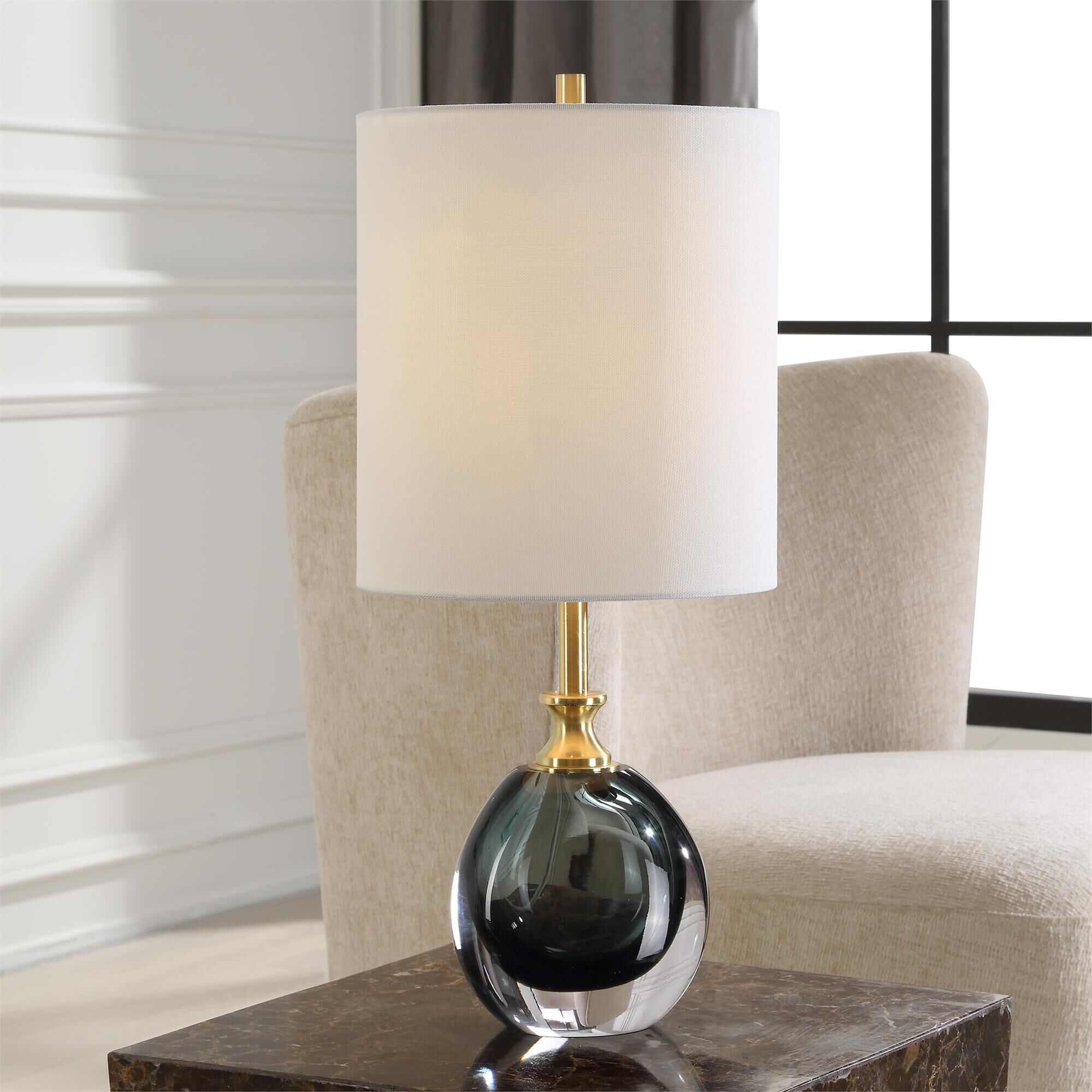 Shown in The Enigma Buffet Lamp Showcases A Smoky Teal Blue Art Glass Body Paired With Brass Plated Details A finish and Round Hardback shade