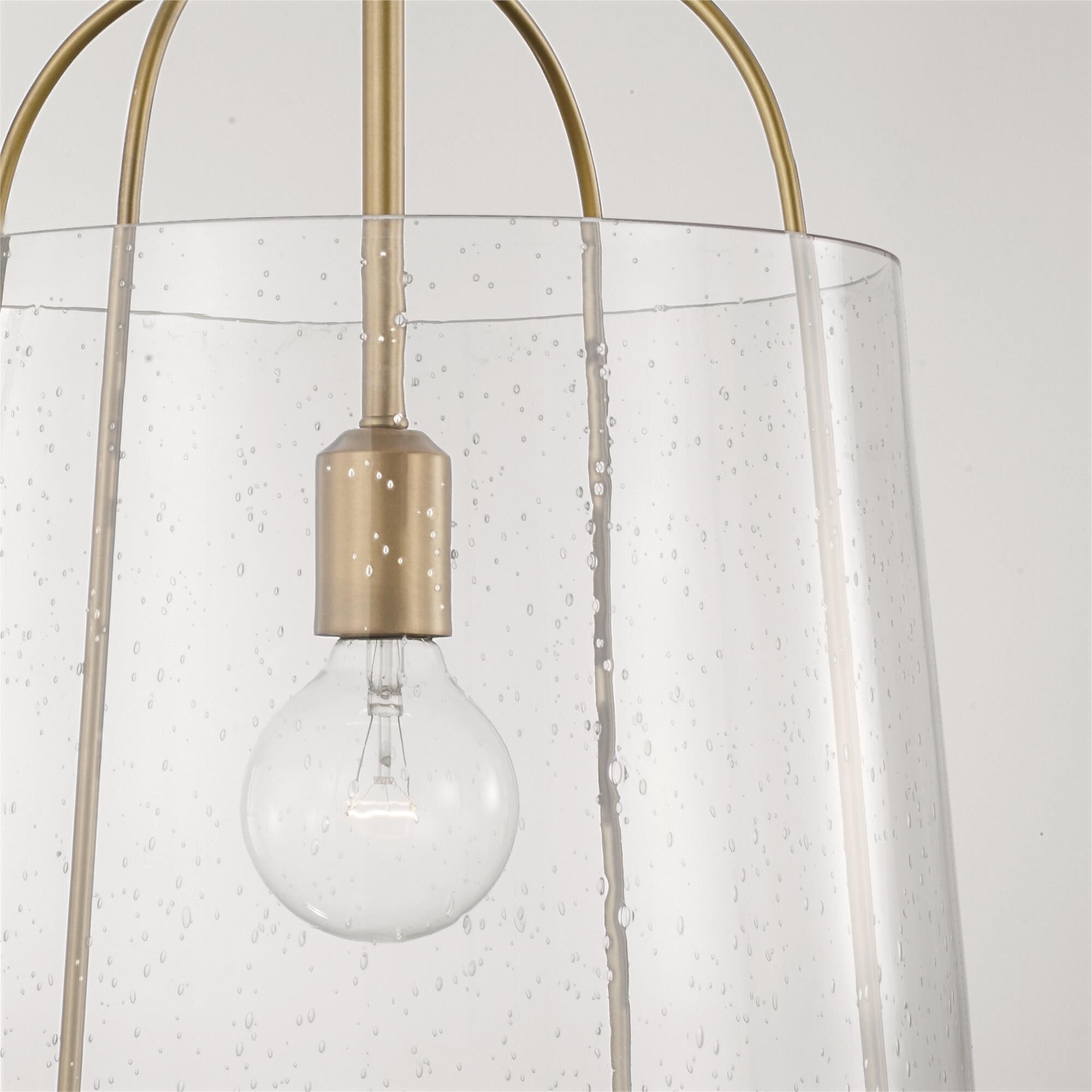 Shown in Aged Brass finish and Clear Seeded glass