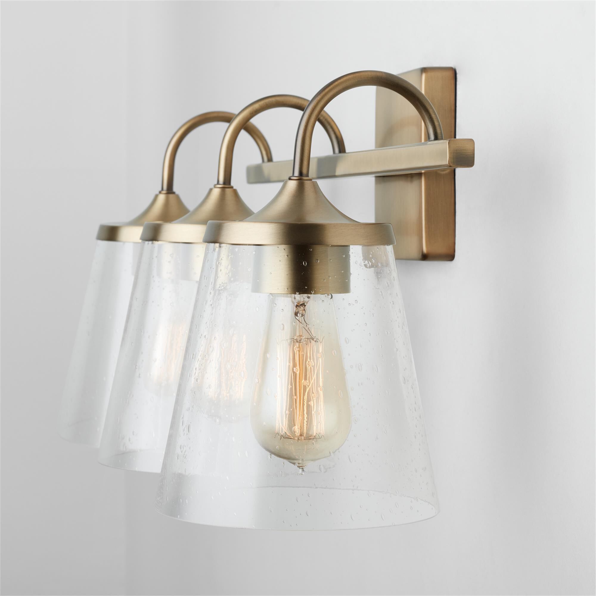 Shown in Aged Brass finish and Clear Seeded glass