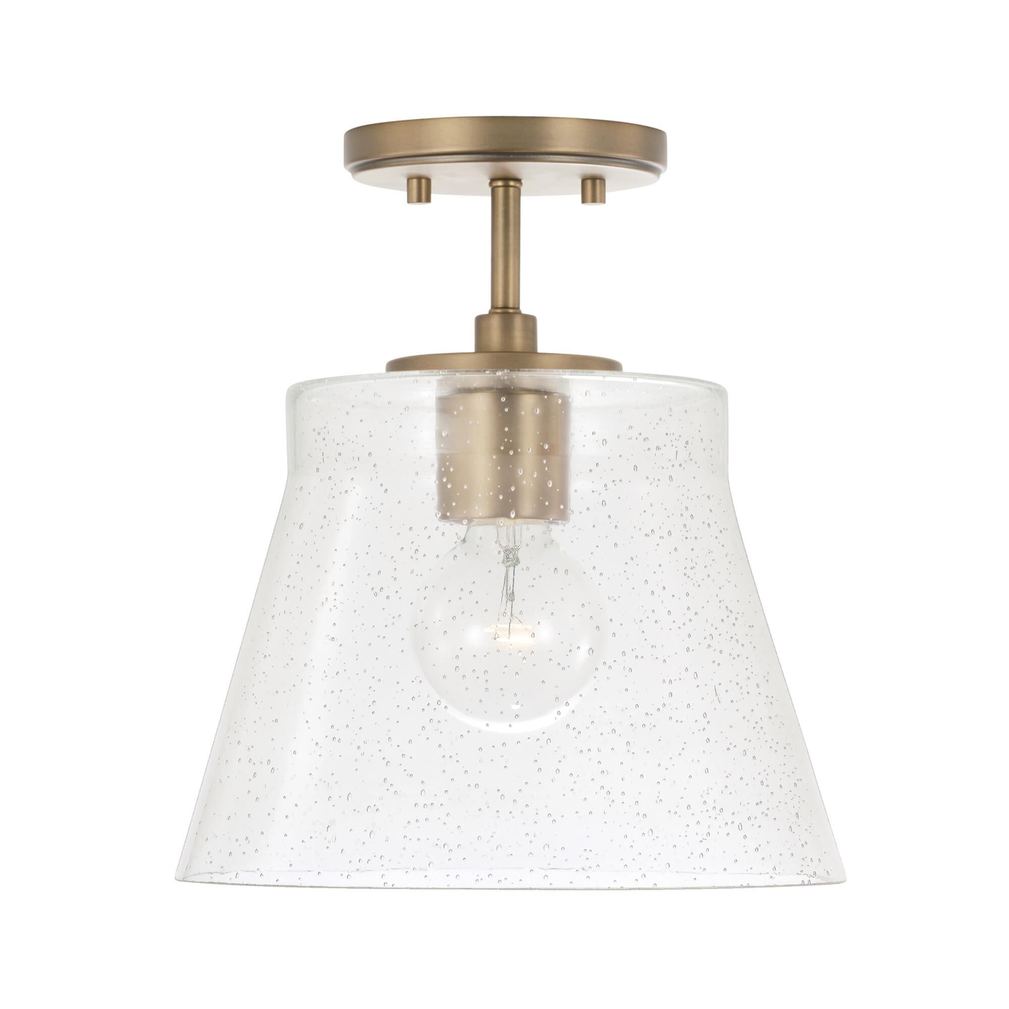 Shown in Aged Brass finish and Clear Seeded glass