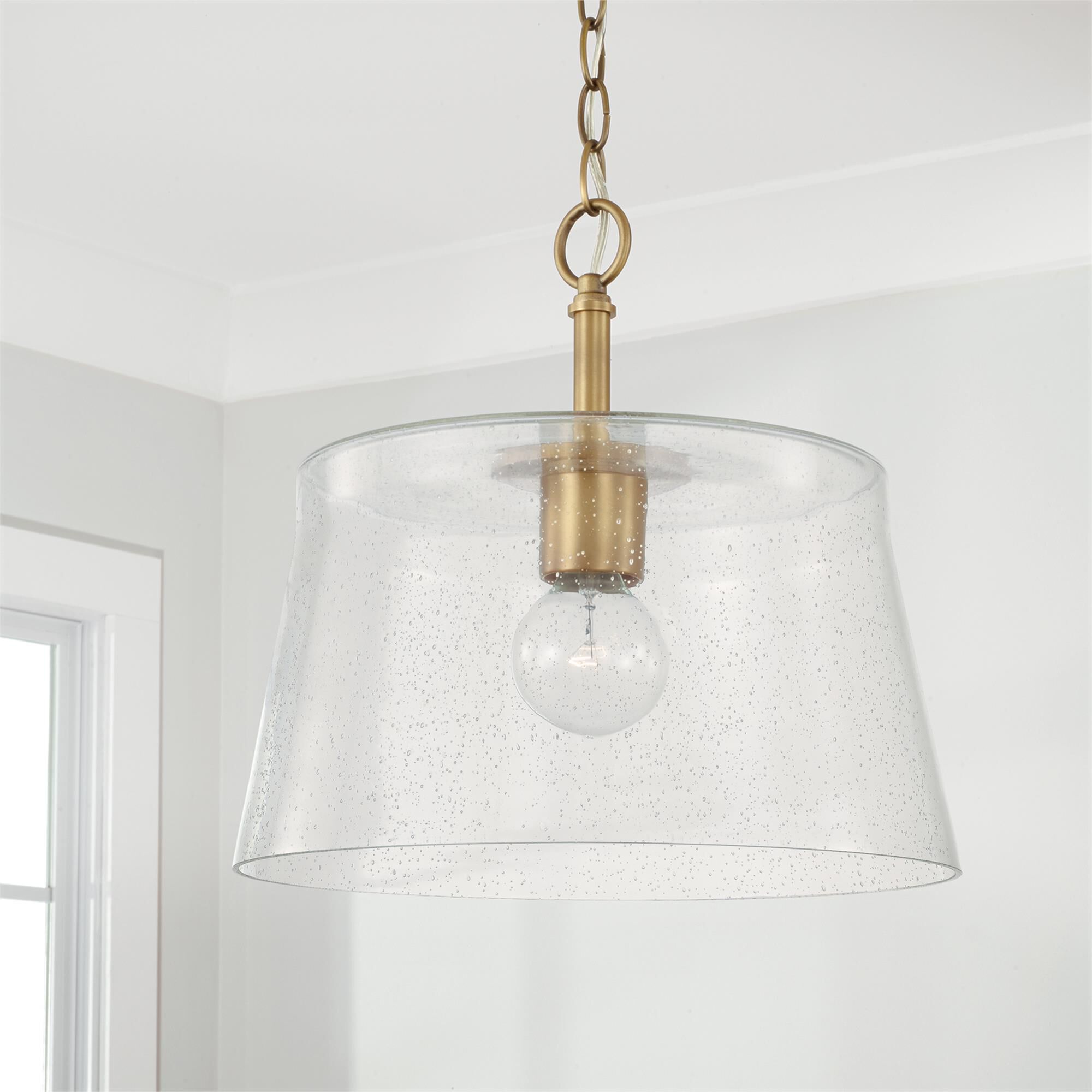 Shown in Aged Brass finish and Clear Seeded glass