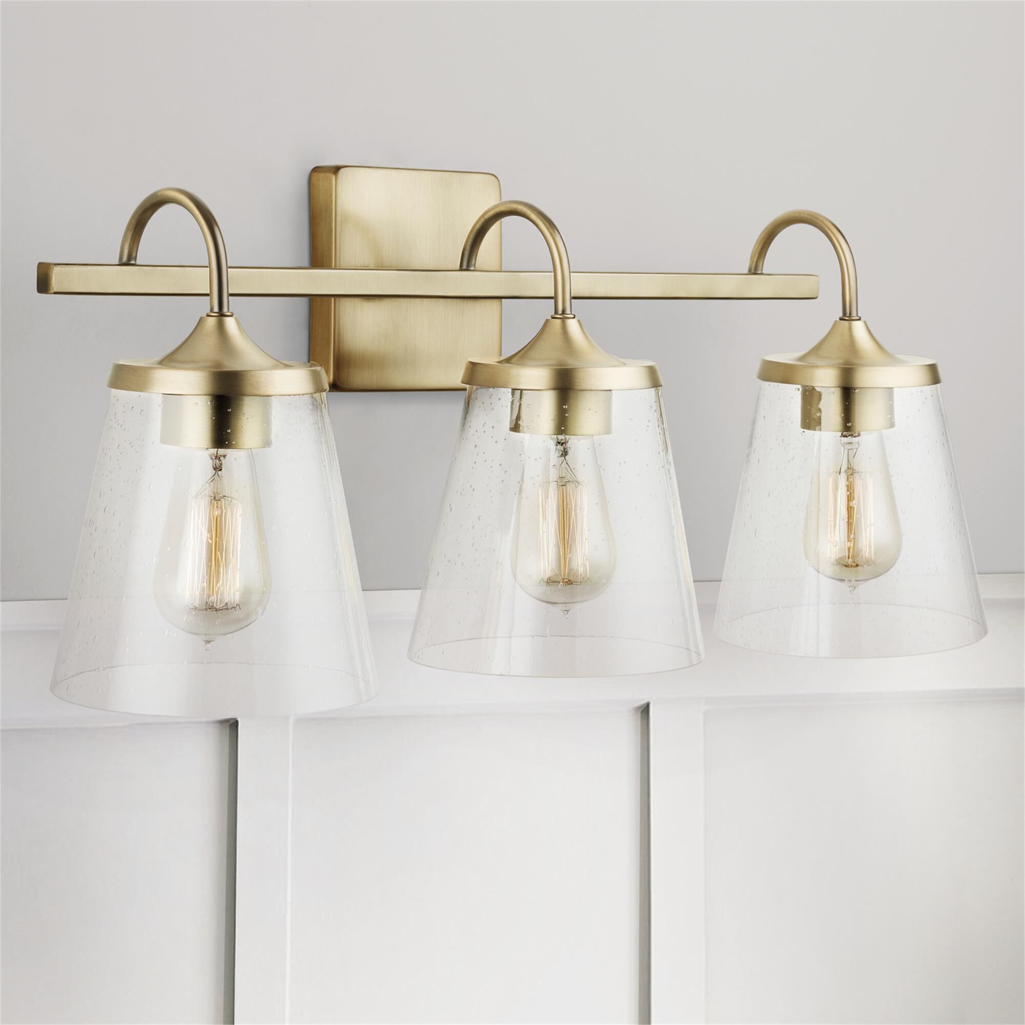 Shown in Aged Brass finish and Clear Seeded glass