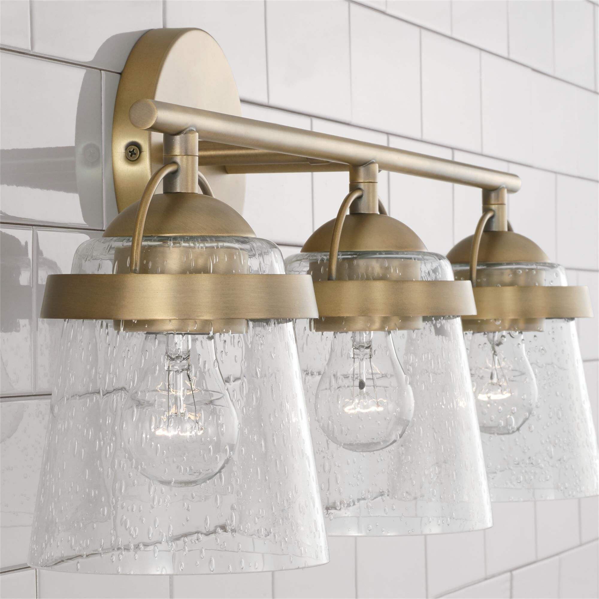 Shown in Aged Brass finish and Clear Seeded glass