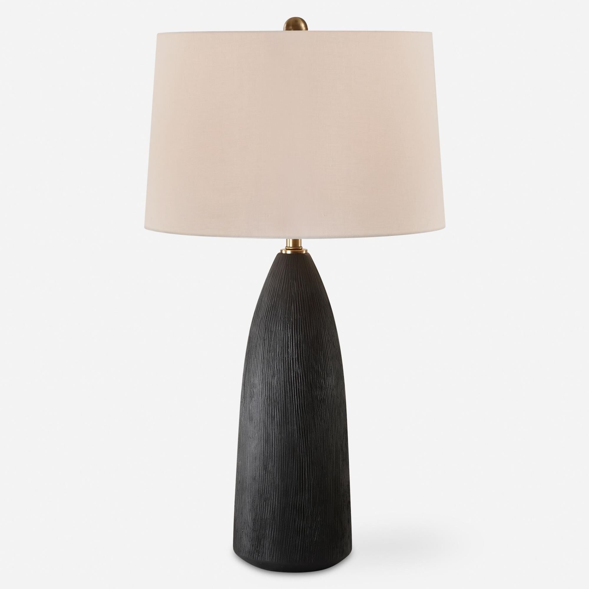 Shown in The Jett Table Lamp Showcases A Matte Black Ceramic Base With Organic Texturing, Accented With Plate finish and Round Hardback shade
