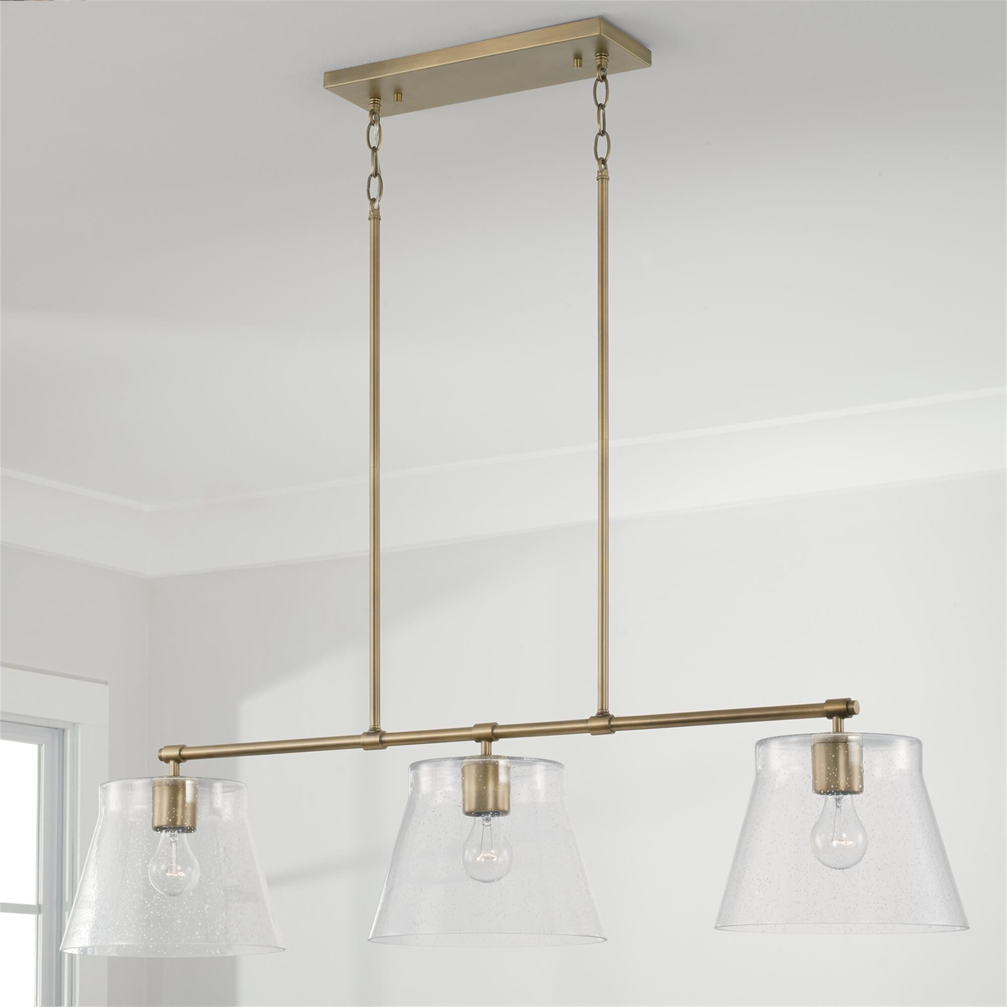 Shown in Aged Brass finish and Clear Seeded glass