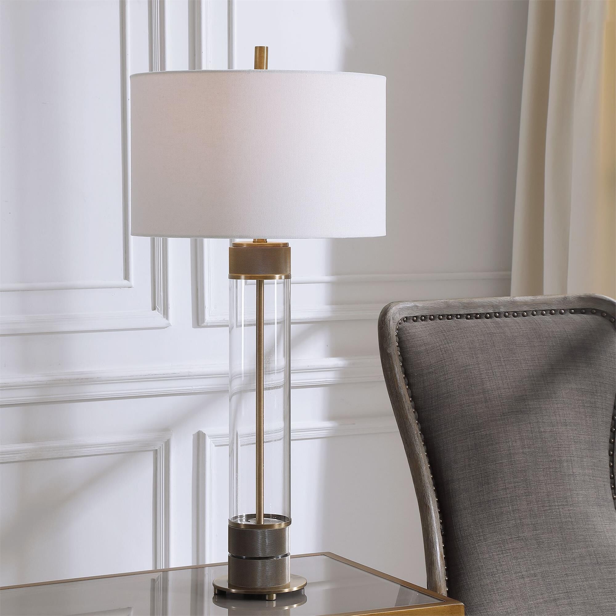 Shown in Showcasing A Clean Transitional Look, This Table Lamp Features A Clear Glass Base Accented With Anti finish and Round Drum Hardback shade
