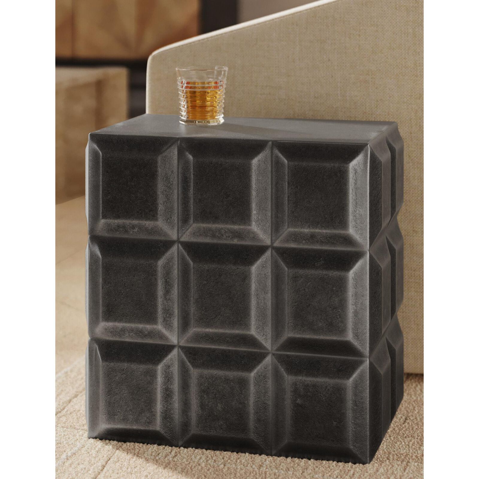 The Bower End Table in a living room setting with a glass on top.