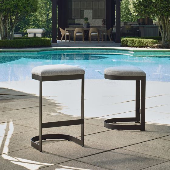 Two stools with gray frames and seats outdoors by a pool.
