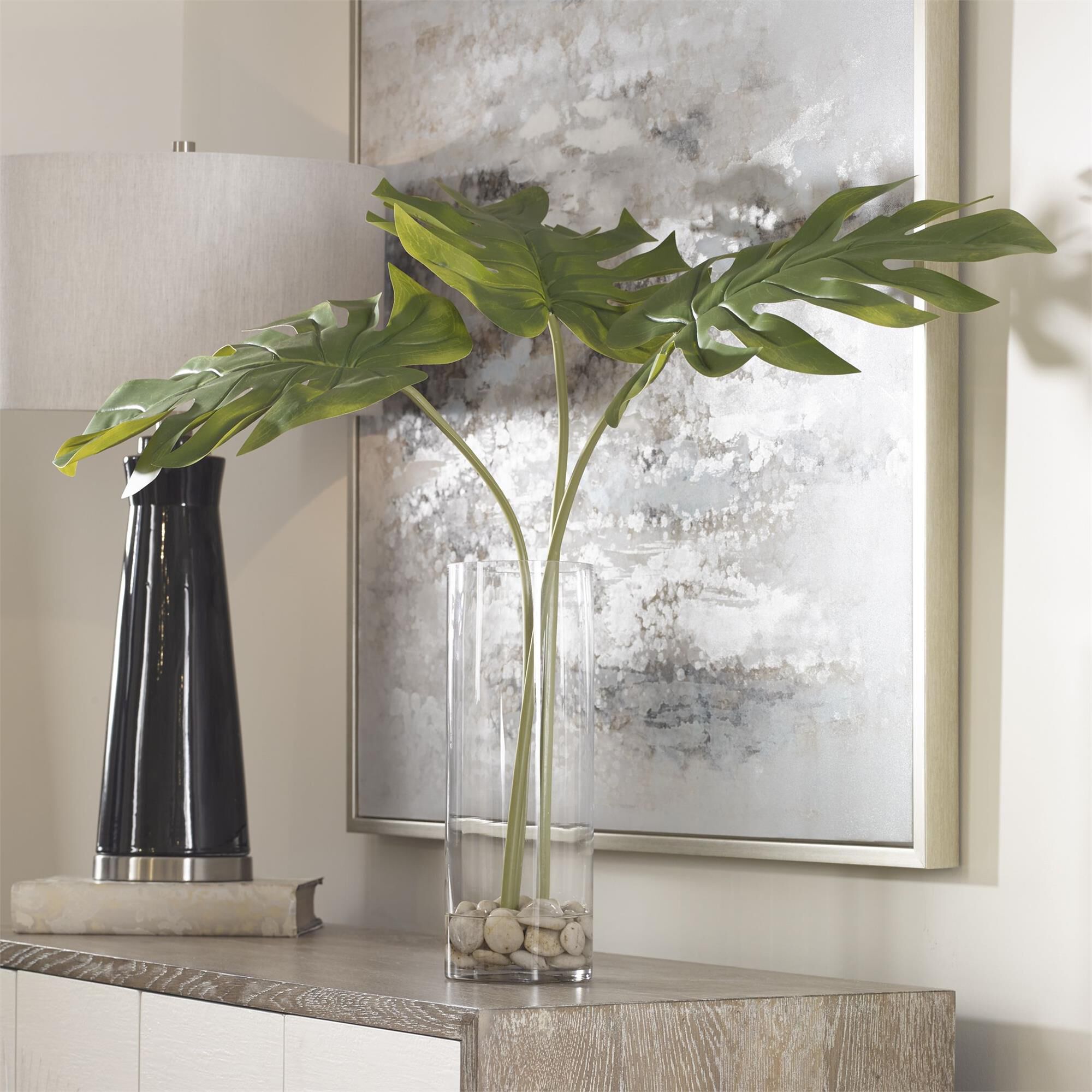 Shown in Contemporary Split Leaf Palm Trio Artfully Arranged In A Clear Glass Cylinder Vase With Natural Ston finish
