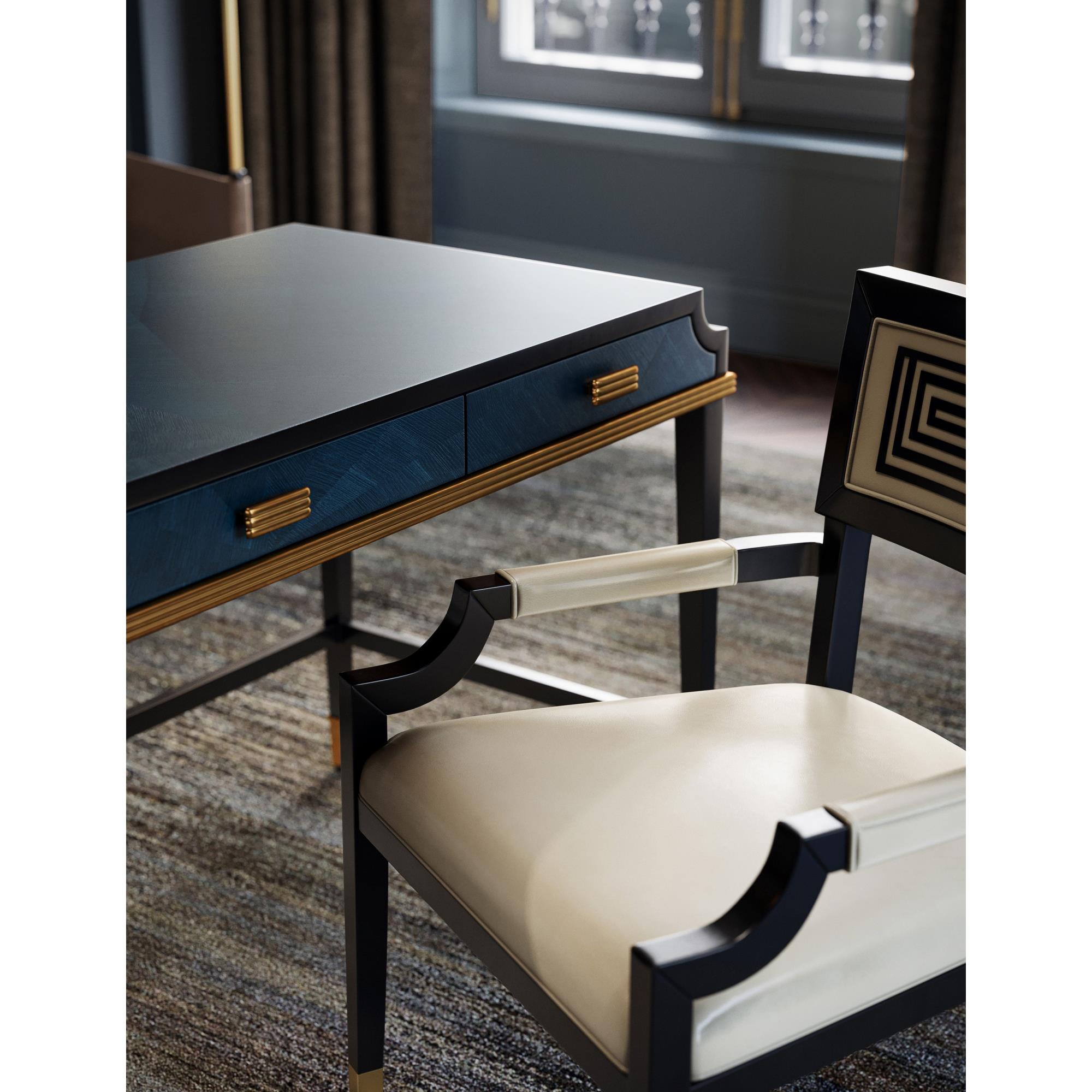 Close-up of the desk work surface and a chair with cream upholstery, showing the drawer handles and blue wood with gold trim.